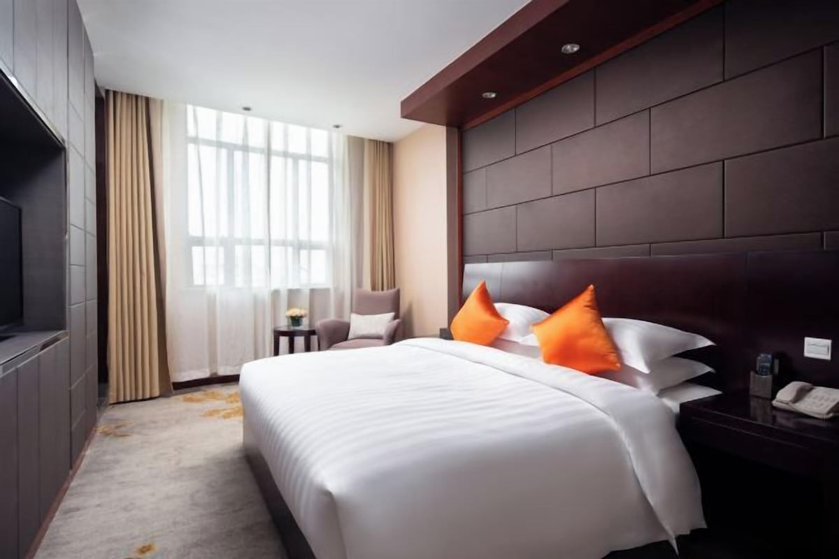 A hotel room with a large bed, a television, a small table, and a chair.