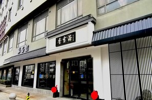 A hotel facade with signage, large windows, and a gated entrance. - Xiangxuehai Hotel (Suzhou)