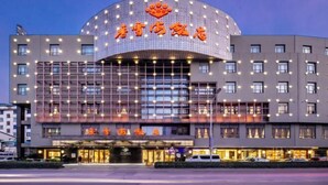 A modern hotel with a curved facade, multiple floors, and a prominent sign with illuminated characters. - Xiangxuehai Hotel (Suzhou)