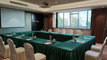 A conference room with a long table, chairs, and a projector screen.