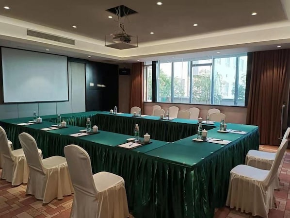 A conference room with a long table, chairs, and a projector screen. - Xiangxuehai Hotel (Suzhou)