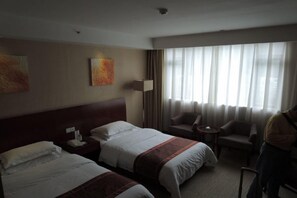 A hotel room with two beds, a sitting area with a chair, a lamp, and artwork on the wall. - Xiangxuehai Hotel (Suzhou)