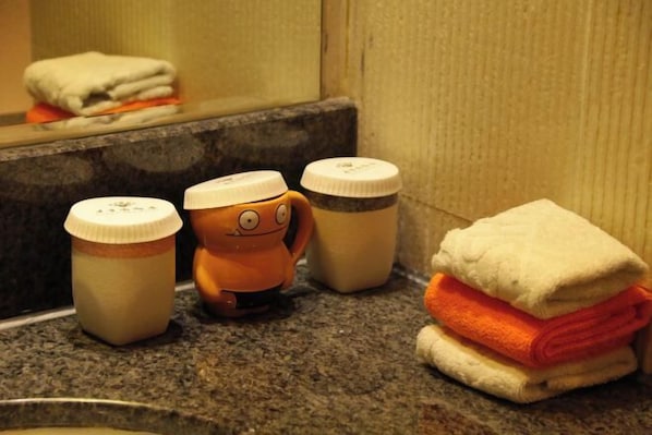 A bathroom counter with a towel stack, a small orange toy, and two bottles.