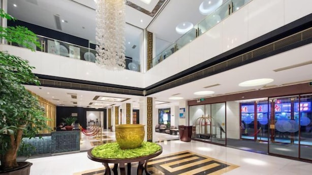 A modern hotel lobby with a high ceiling, a central decorative column, and a reception desk. - Xiangxuehai Hotel (Suzhou)