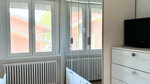 Une pièce avec un grand miroir, une commode blanche et un radiateur.