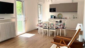 Une cuisine moderne équipée d’un téléviseur, d’un coin repas avec une table et des chaises, et d’un plancher en bois.