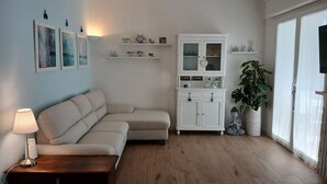Un salon avec un canapé, un meuble, une lampe et une plante en pot.