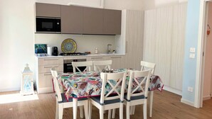 Une cuisine compacte équipée d’un four à micro-ondes, d’une cuisinière et d’un évier, ainsi qu’une table à manger avec des chaises et un lustre.