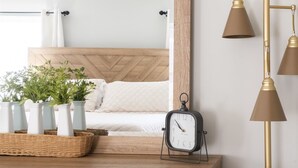 Un aparador de madera con espejo, un reloj y jarrones decorativos.