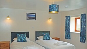 A double room with two beds, a nightstand, a bedside table, a window with curtains, and a wall-mounted picture. - Beech Cottage - UK49564 (Sneaton, near Whitby)