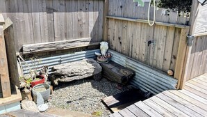 A wooden deck with a rustic fence, a metal bucket, and a potted plant.
