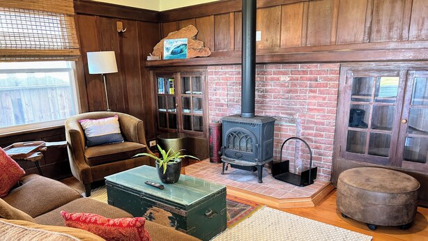A cozy living room with a brick fireplace, wooden furniture, and a green chest.