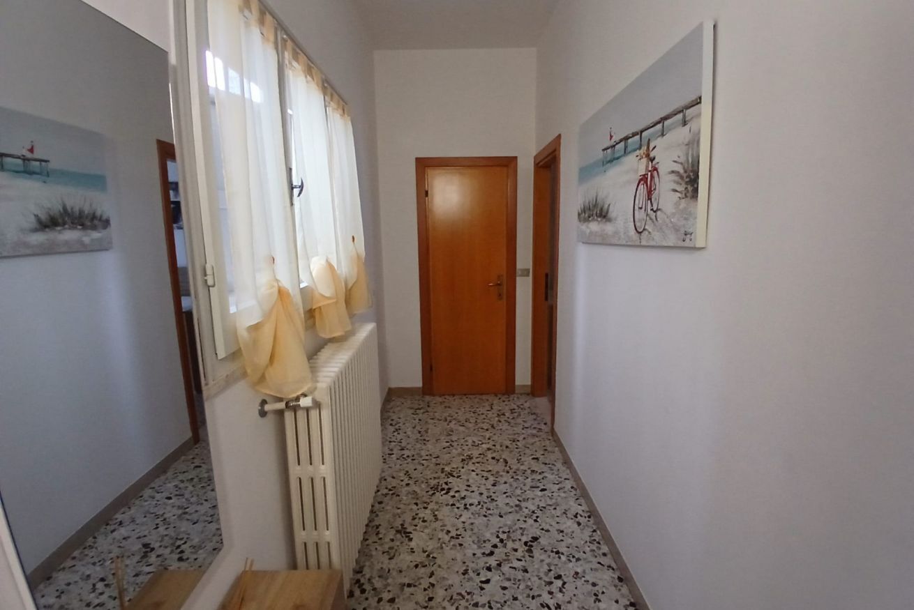 Un pasillo con un radiador, una puerta de madera y un cuadro de una bicicleta en la pared.