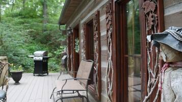 A wooden deck with outdoor furniture, a barbecue grill, and a statue.