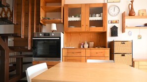 A kitchen with wooden cabinets, a stove, and a dining table with chairs. -  M419 – Marcelli, one bedroom apartment eith terrace and air conditioning (Marcelli)