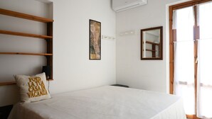 A bedroom with a bed, a wooden shelf, a painting, a mirror, and a window. -  M419 – Marcelli, one bedroom apartment eith terrace and air conditioning (Marcelli)