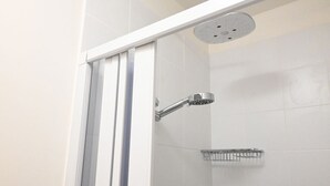 Eine Duschkabine mit Glastür, Handbrause und Ablagefach aus Metall.