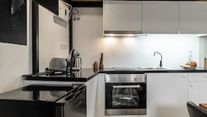A modern kitchen with a black stove, white cabinets, and a stainless steel oven. - The Naxos Loft with view of the Castle (Naxos)