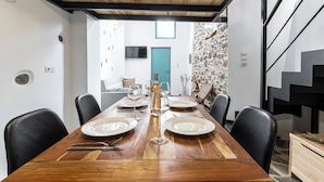 A dining area with a wooden table set for four, black chairs, and a stone wall in the background. - The Naxos Loft with view of the Castle (Naxos)