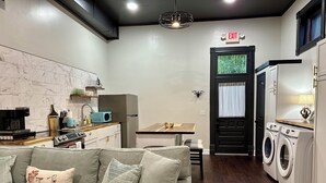 A modern living room with a sofa, a coffee machine, and a small table. - Katy Suite - Chic 2BR Stay on Katy Trail in Historic Mercantile near Hermann (Hermann)