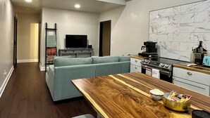 A modern kitchen with a wooden dining table, a built-in oven, and a marble backsplash. - Katy Suite - Chic 2BR Stay on Katy Trail in Historic Mercantile near Hermann (Hermann)