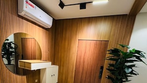 A modern bathroom with a wooden vanity, a round mirror, a built-in bench, and a potted plant.