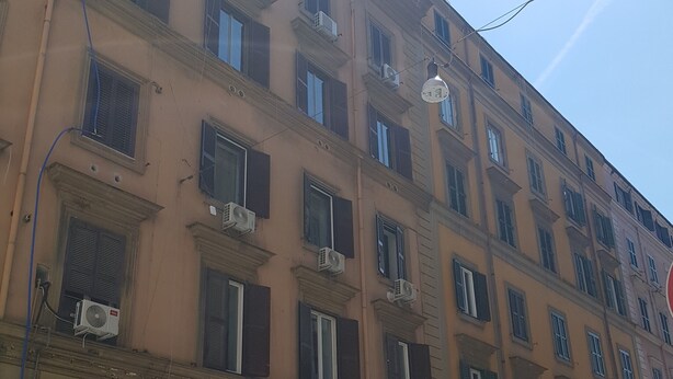 Un immeuble à plusieurs étages, doté de nombreuses fenêtres, dont certaines sont équipées de volets, et de climatiseurs fixés à la façade extérieure.
