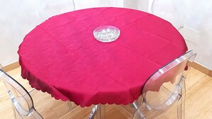 Une table ronde recouverte d’une nappe rouge, agrémentée d’un centre de table décoratif en verre.