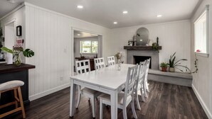 A dining area with a white table and chairs, a fireplace, and a view of the outdoors.