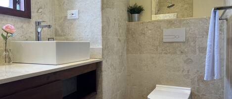 A bathroom with a white sink, a toilet, and a shower area.