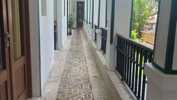 Un couloir doté d’un sol à motifs, de murs blancs et d’un balcon agrémenté d’une balustrade.