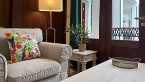 A living room with a sofa, a lamp, a small table with a plant, and a window with a view of a balcony. - Boutique Hotel Casa Grande, Tropical Journey Familiar Suite, 2 BR (Santo Domingo)