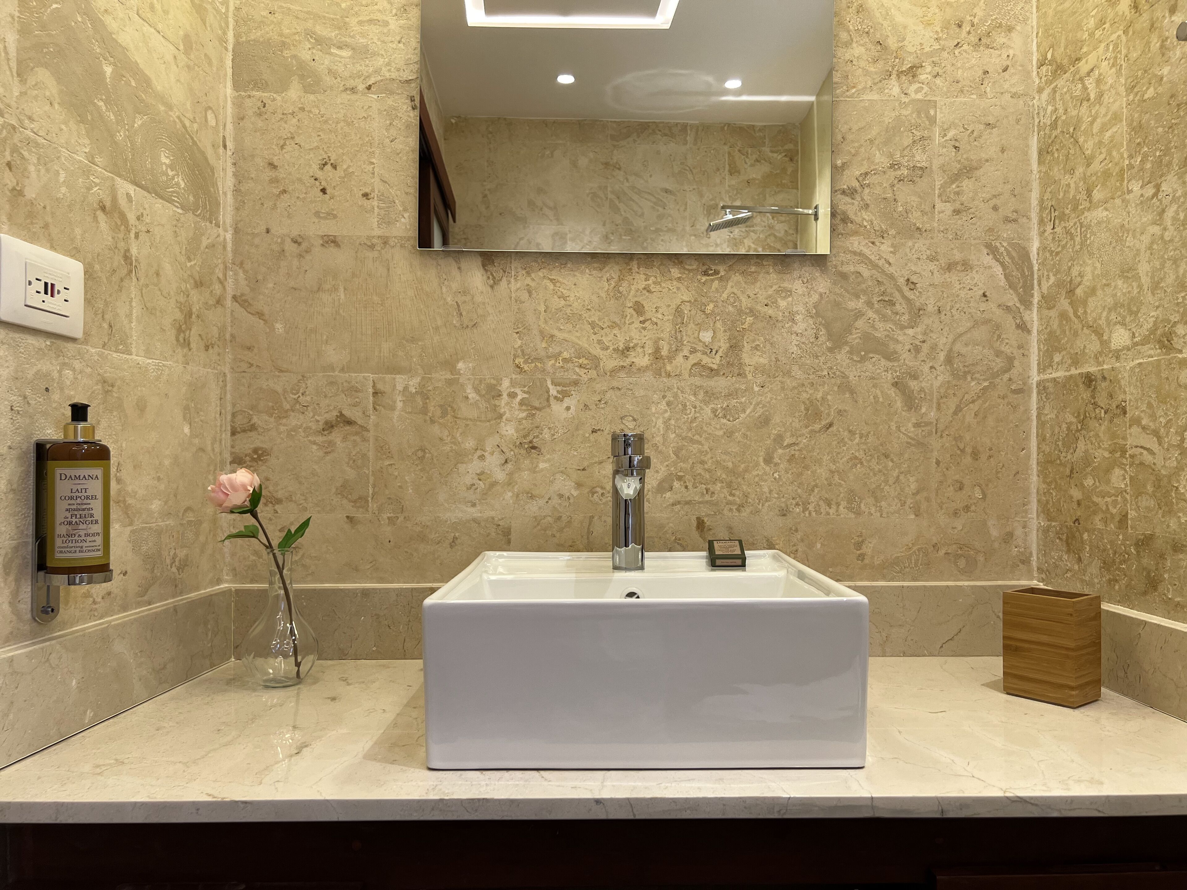 A bathroom with a white sink, a handheld showerhead, and a mirror above it.