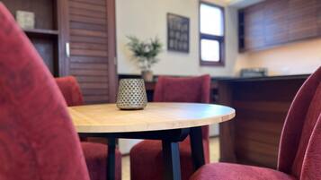 A dining area with a round table, red upholstered chairs, a patterned vase, and a potted plant.