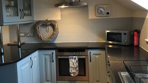 Une cuisine moderne équipée d’un four encastré, d’un four à micro-ondes et d’une cuisinière à gaz.