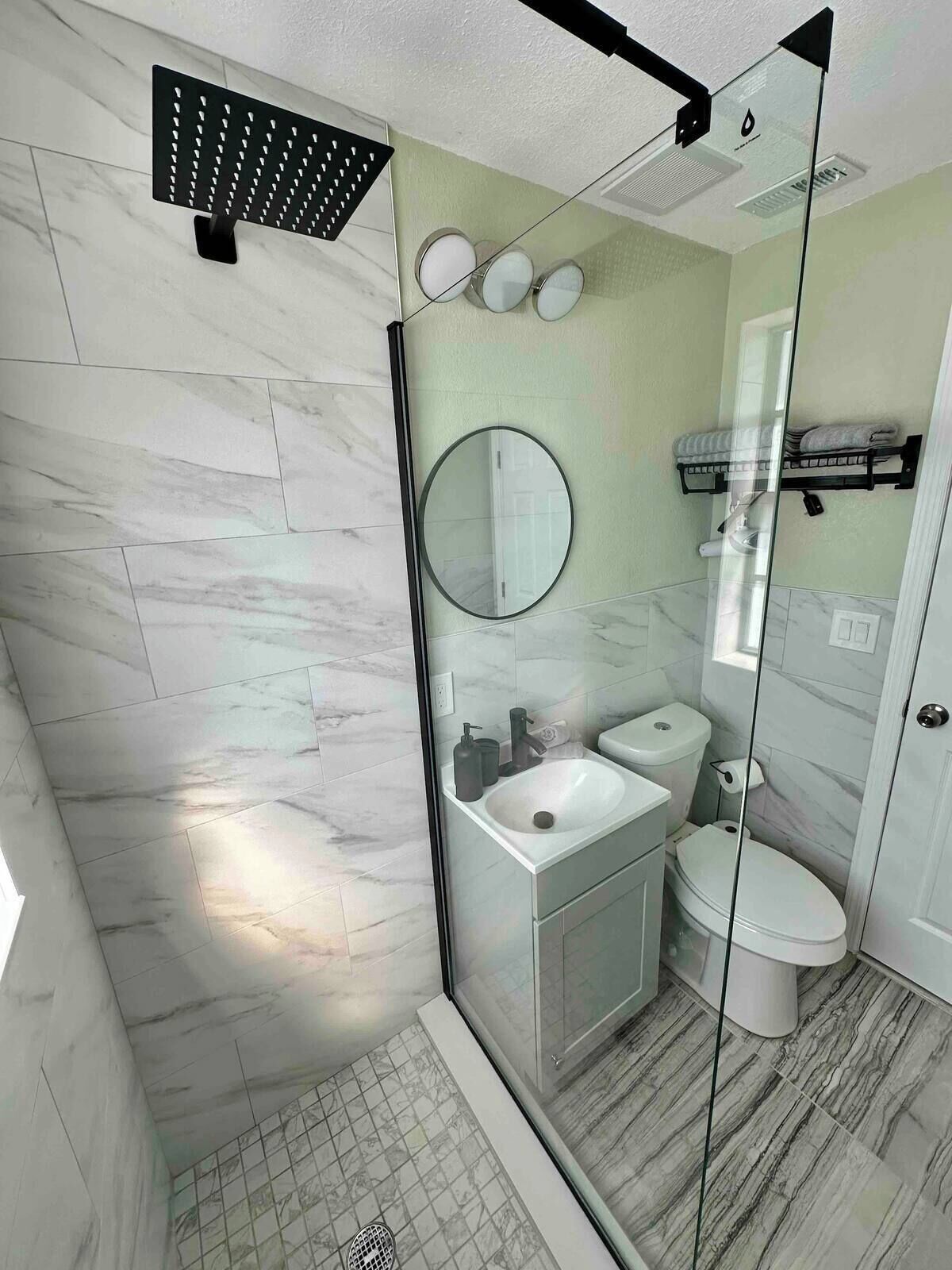 Une salle de bain moderne avec une douche à parois de verre, un lavabo blanc et des toilettes.