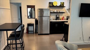 A modern kitchen with a stainless steel refrigerator, a dining table with chairs, and a striped sofa. - Charming 2-bedroom house with POOL, AC, WiFi in lovely Fort Lauderdale (Fort Lauderdale)