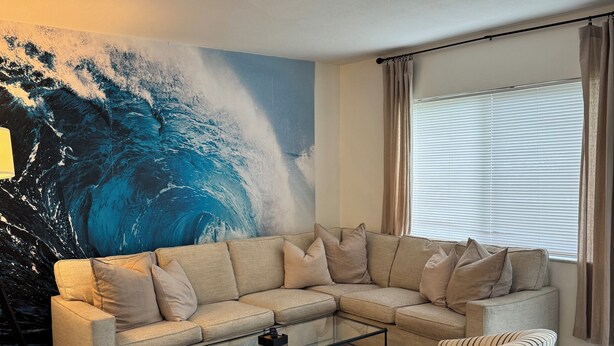A living room with a sectional sofa, a glass coffee table, and a striped armchair. - Charming 2-bedroom house with POOL, AC, WiFi in lovely Fort Lauderdale (Fort Lauderdale)