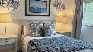 A neatly arranged bedroom with a bed, two bedside tables, a framed picture, and decorative wall art. - Charming 2-bedroom house with POOL, AC, WiFi in lovely Fort Lauderdale (Fort Lauderdale)