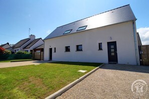Ein modernes, zweigeschossiges Haus mit Flachdach, Eingangstür und einer kleinen Auffahrt.