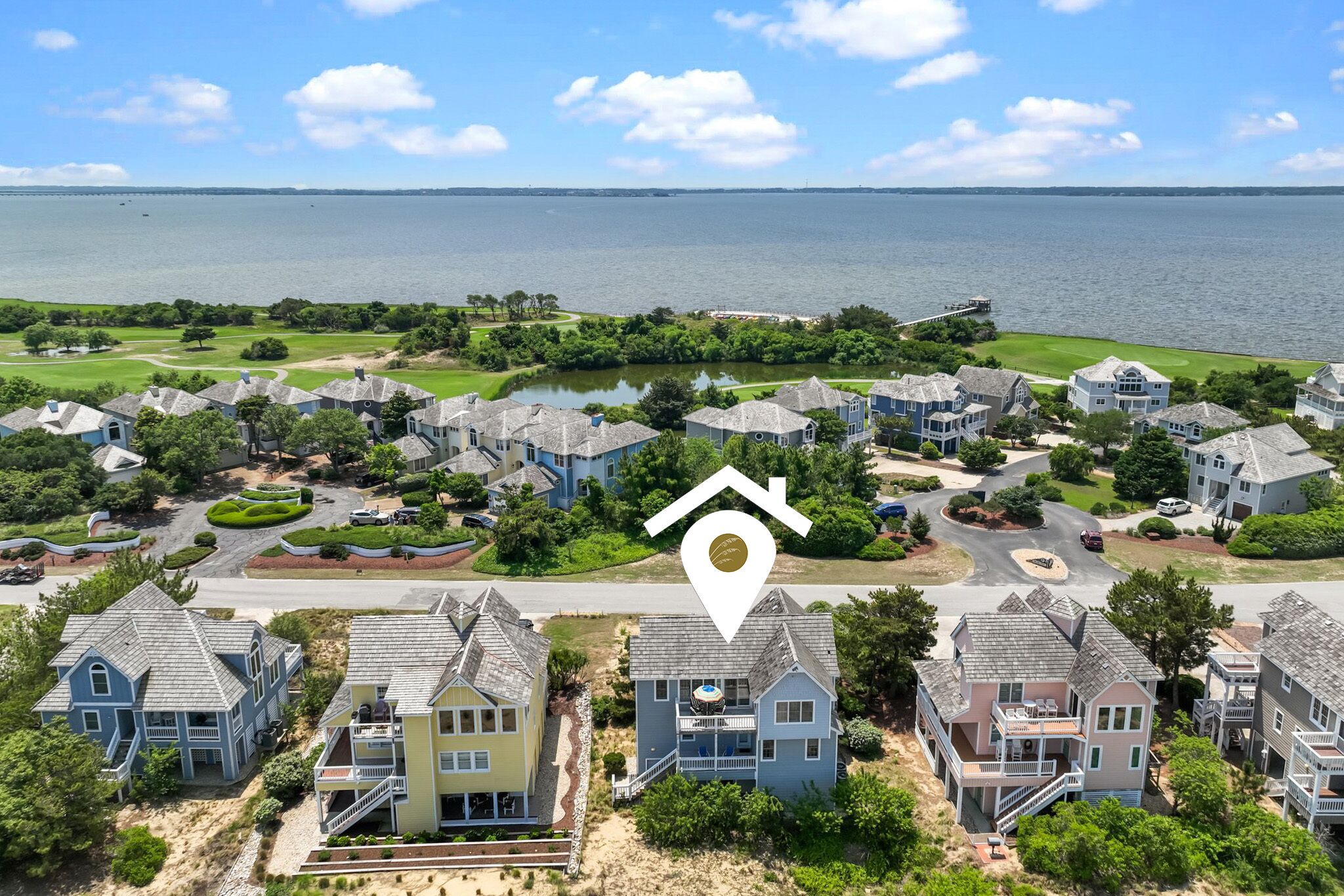 A coastal residential area with houses, a golf course, and a view of the ocean.
