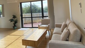 A spacious living room with a wooden coffee table, a beige sofa, and a potted plant.