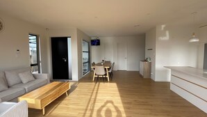 A modern living room with a sofa, coffee table, and dining area.