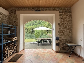 An open doorway leading to an outdoor patio with a table and chairs, surrounded by stone walls and a wooden ceiling.
