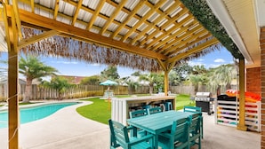 A covered patio with a pool, outdoor furniture, and a barbecue area. - Tropical Feel, Heated Pool, Hot Tub, Game Room, Mini Golf (Panama city beach)