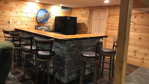 A bar area with a stone counter, wooden chairs, and a sign for 'Jack Daniel's'. - Clearfield Co Rockton PA - Cabin Escape (Rockton)