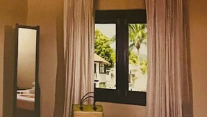 A hotel room with a bed, a window with curtains, a bedside table with a lamp, and a mirror on the wall. - Tranquil resort with 2 bedrooms and AC, WiFi in Puerto Plata (Puerto Plata)