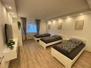 Een moderne slaapkamer met twee eenpersoonsbedden, een klein bureau, een radiator en een raam met gordijnen.