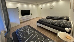 Een moderne slaapkamer met een televisie, twee bedden, een nachtkastje en een kledingkast.