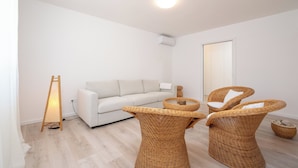 A modern living room with a sofa, two wicker chairs, a small side table, and a floor lamp. - Beachfront apartments Nincevic (Trogir)